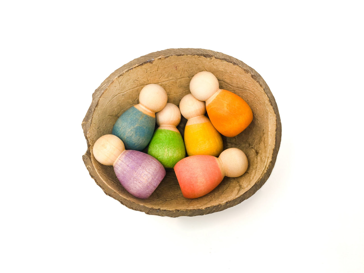 6 wooden babies nestled in a half coconut shell. Each baby nin is painted a different rainbow colour.