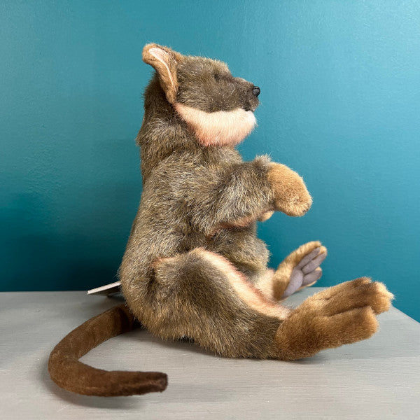 Side view of plush quokka puppetm facing to the right, the tail is visible in the foreground