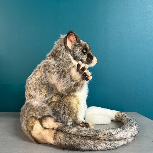 side bview of ring tailed possum puppet toy showing thick tail curled around feet