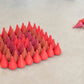 36 small wooden pieces.  They are shaped like a tear drop or flame and are in various shades of red.