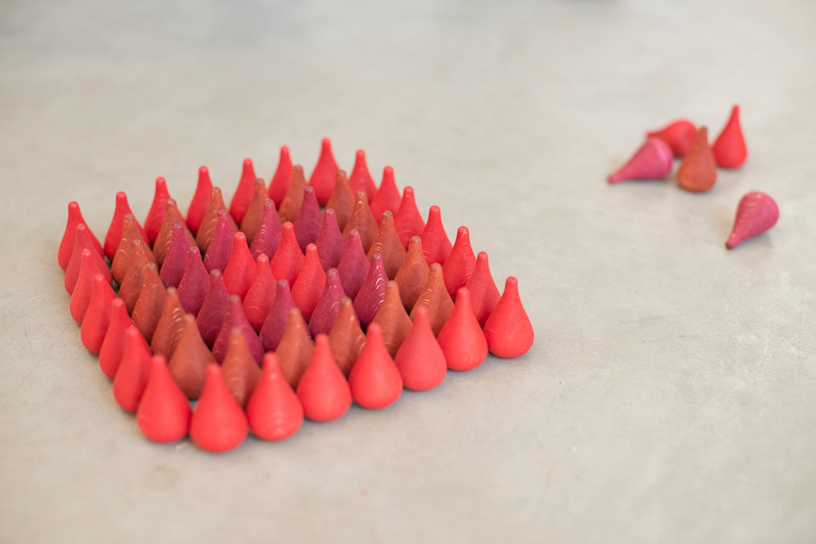 36 small wooden pieces.  They are shaped like a tear drop or flame and are in various shades of red.