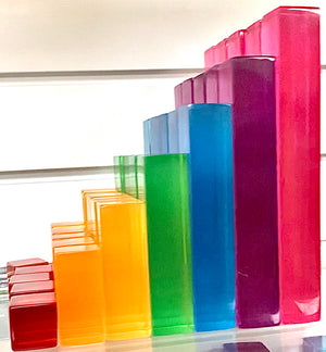 A set of coloured lucite rods.  Smallest block (cube) is red, then orange, yellow, green, blue, purple and pink.  There are 5 block of each colour.