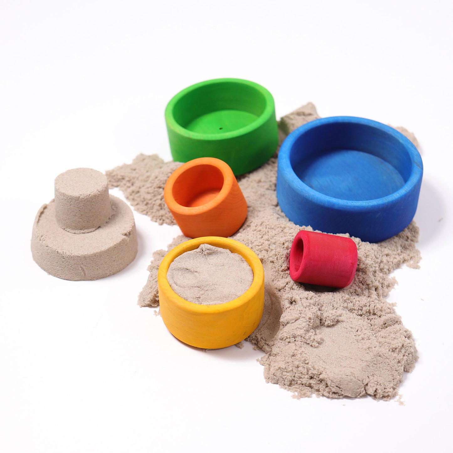 Five bright rainbow wooden bowls are scattered amongst play sand.  A sandcastle has been built using two of the bowls as a mold.